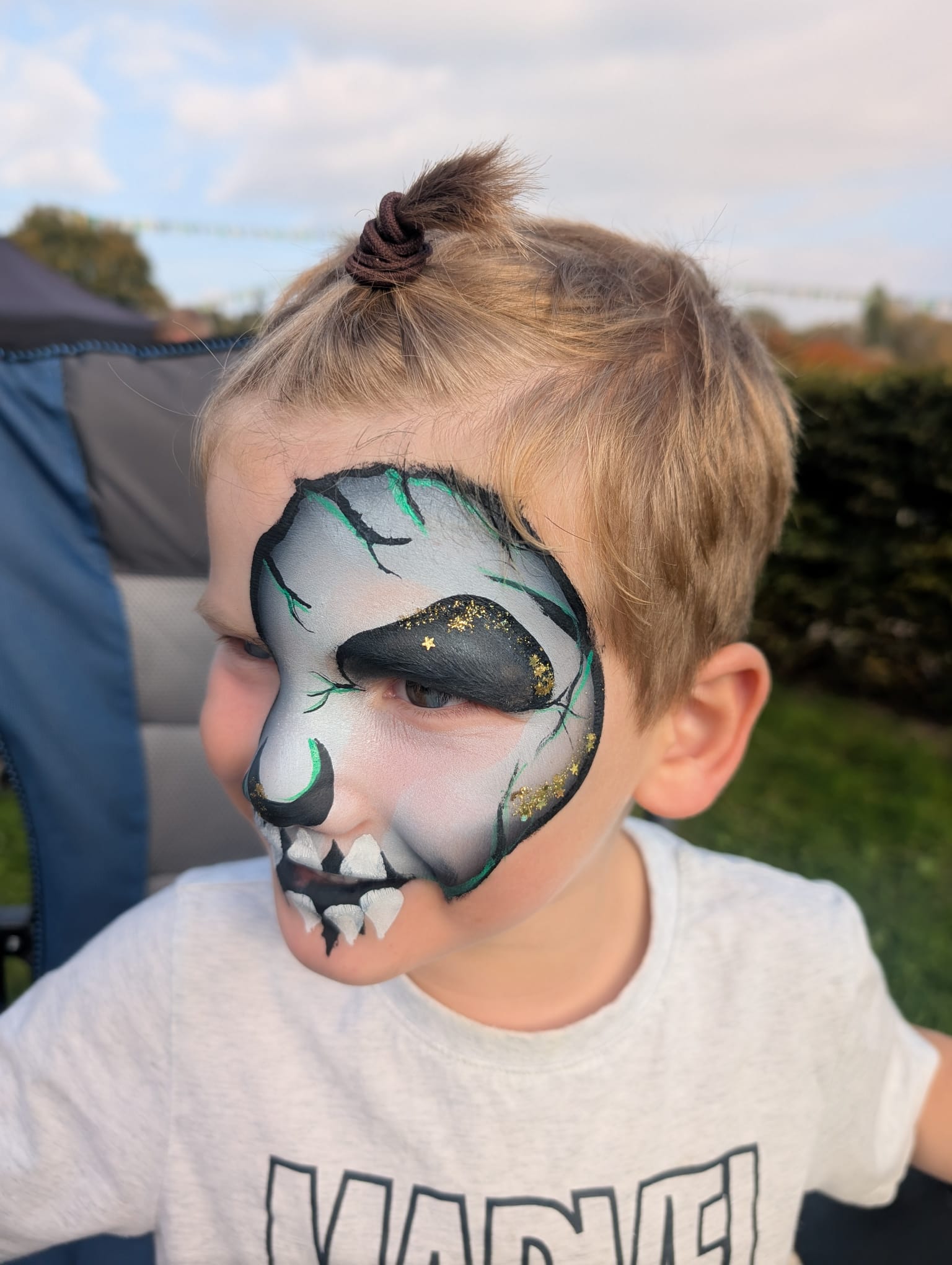 Blue and green monster skull face paint for a boy