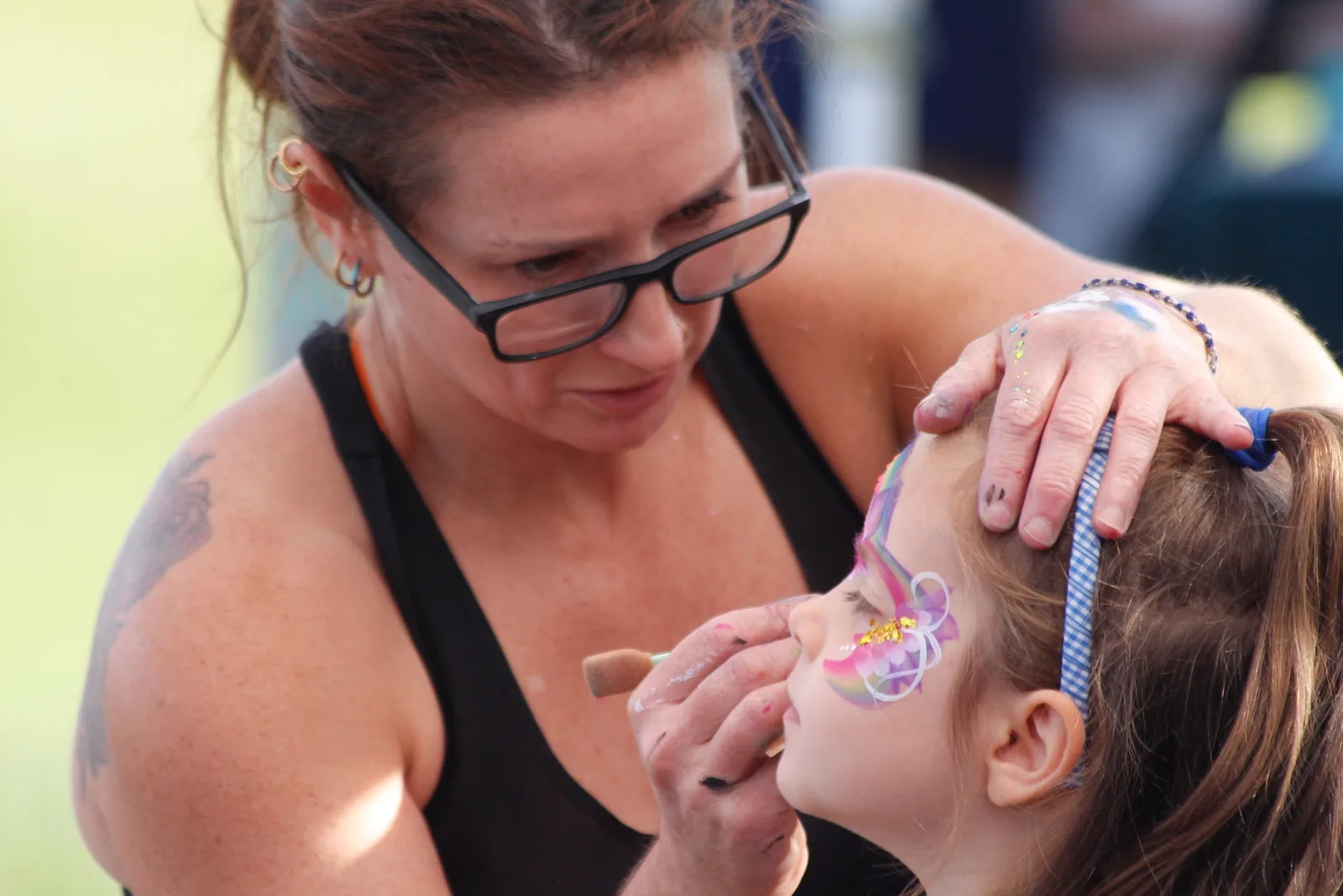 Kat face painting a butterfly design on a girl